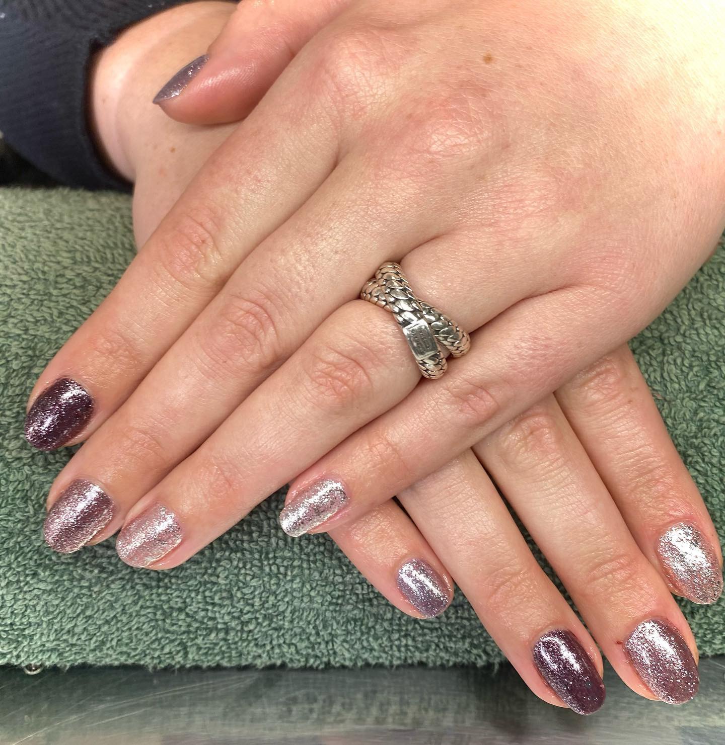 Handen op een groene handdoek met nagels in mauve en roze glitter